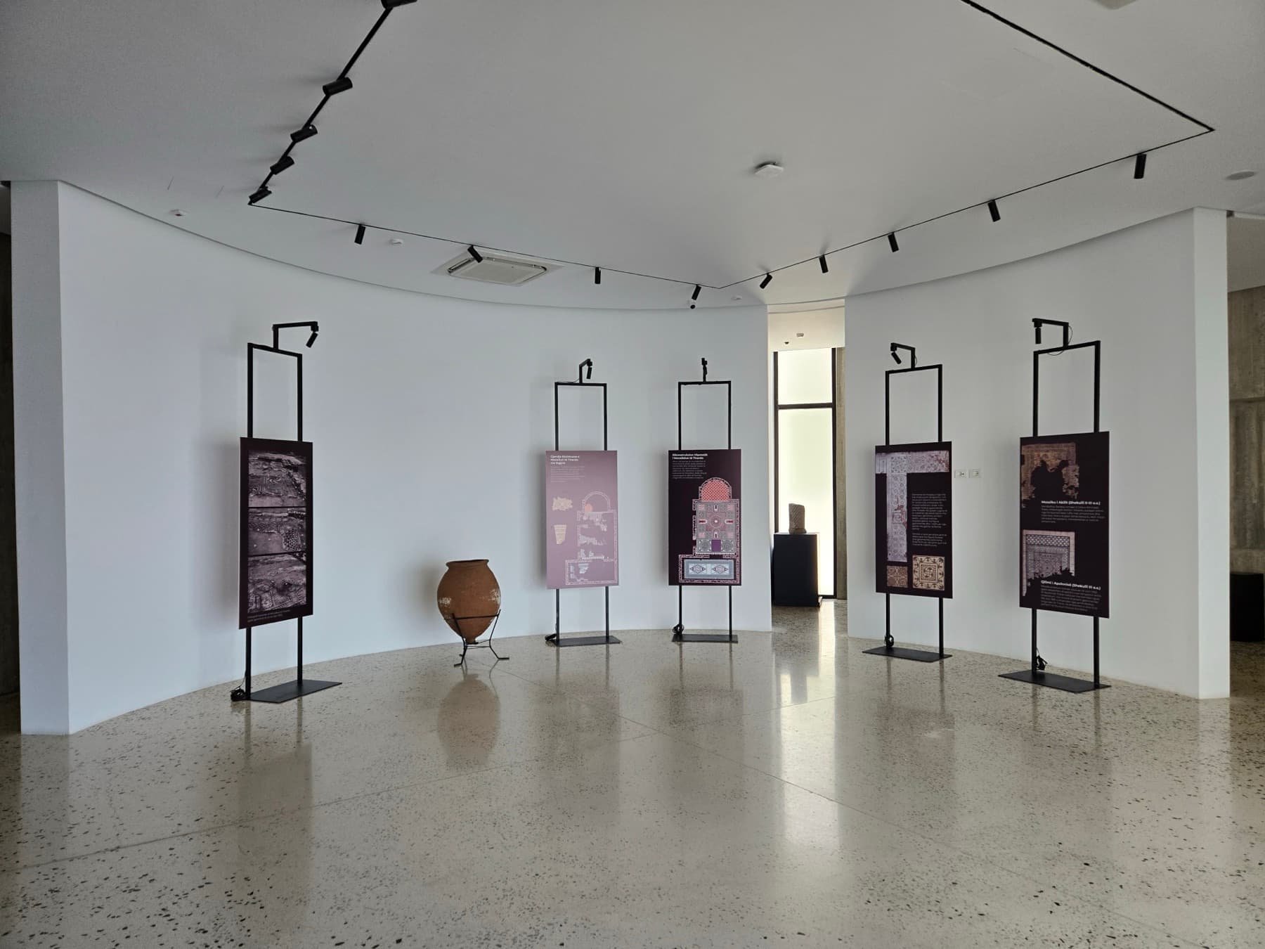 Gallery interior with hanging information panels depicting Albanian mosaic traditions.